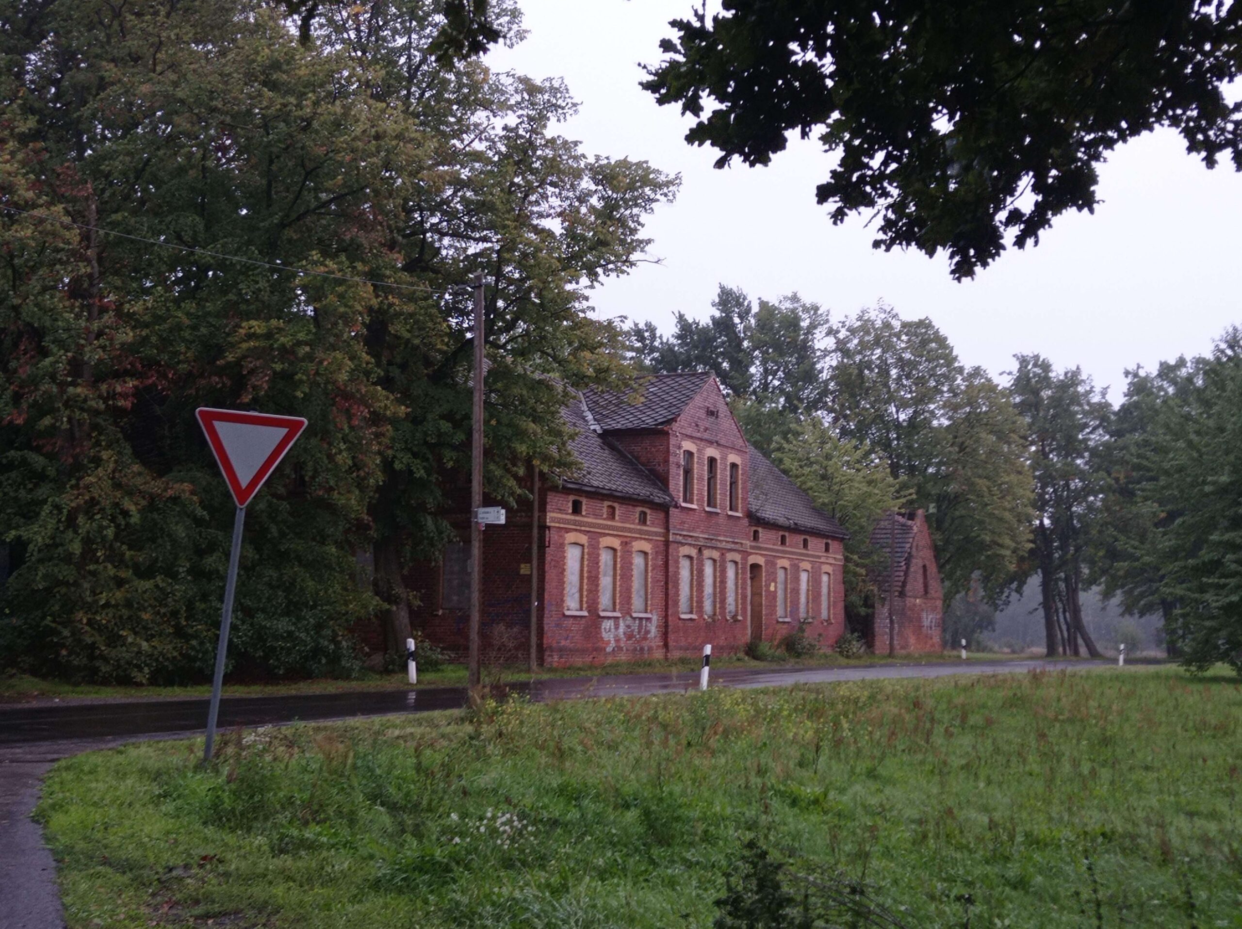 Red-brick building along a road surrounded by trees